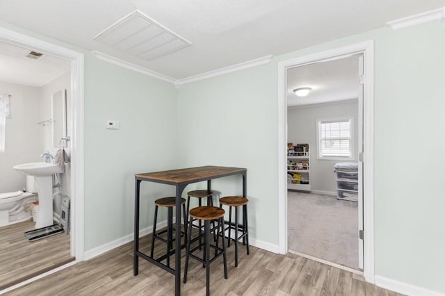 dining area featuring crown molding, sink, and light hardwood / wood-style floors