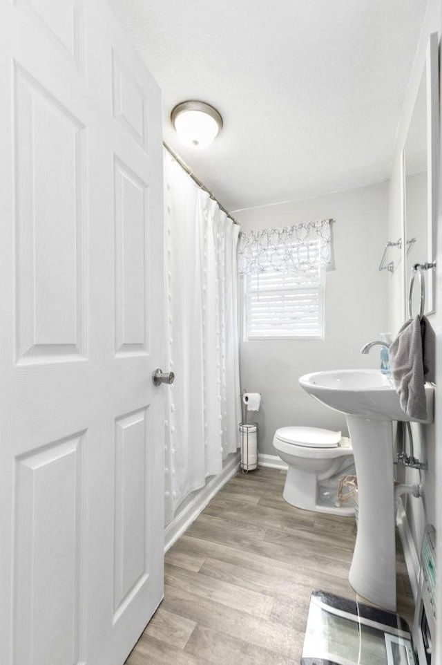 bathroom with hardwood / wood-style floors, shower / bath combo, and toilet