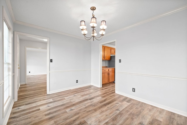 empty room featuring crown molding, an inviting chandelier, and light hardwood / wood-style flooring