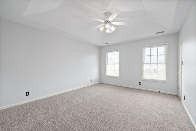 spare room featuring ceiling fan, carpet, a textured ceiling, and a tray ceiling