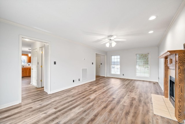 unfurnished living room with crown molding, ceiling fan, a fireplace, and light hardwood / wood-style floors