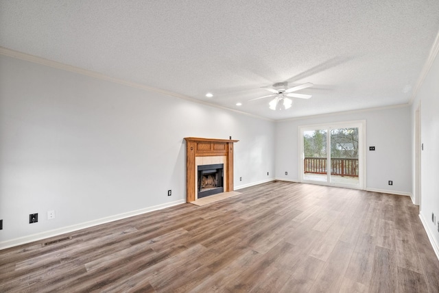 unfurnished living room featuring hardwood / wood-style flooring, a tile fireplace, ceiling fan, ornamental molding, and a textured ceiling