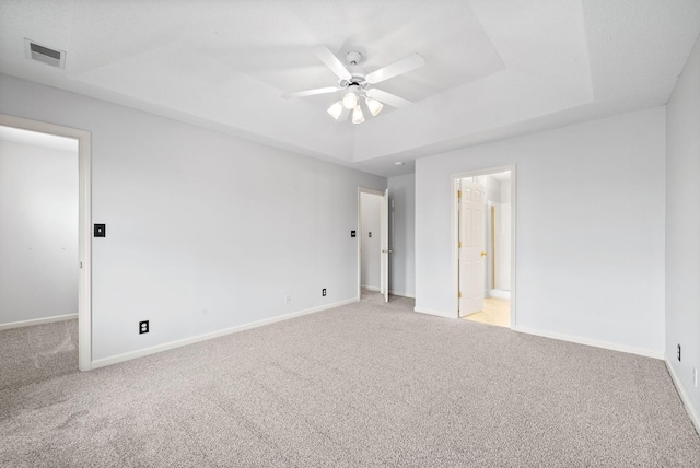 spare room featuring a tray ceiling and light colored carpet