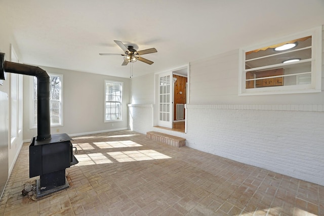 unfurnished living room with a wood stove and ceiling fan