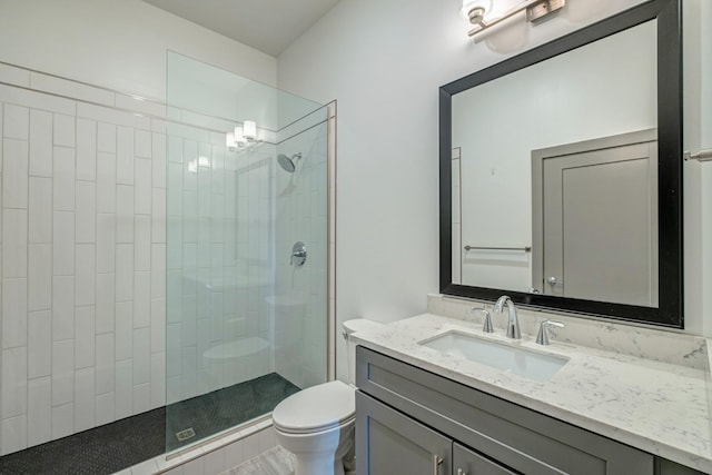 bathroom with vanity, toilet, and tiled shower