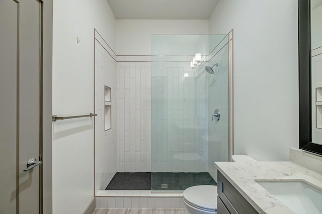 bathroom with vanity, toilet, and tiled shower