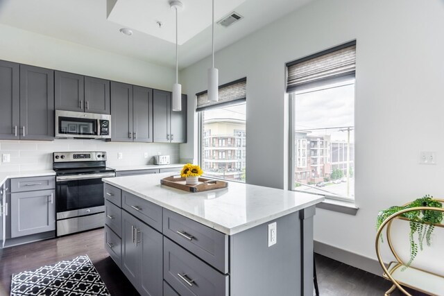 kitchen featuring gray cabinetry, tasteful backsplash, stainless steel appliances, and a center island