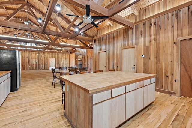 kitchen featuring a large island, stainless steel fridge, wooden counters, vaulted ceiling with beams, and wooden ceiling