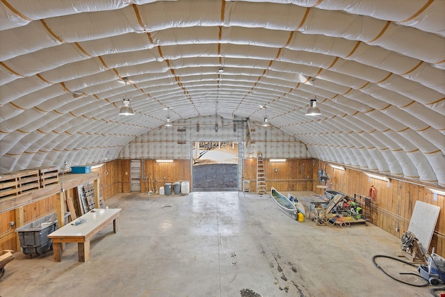 misc room with lofted ceiling, wooden walls, and concrete floors