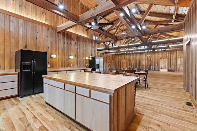 kitchen featuring wood ceiling, a spacious island, stainless steel refrigerator with ice dispenser, black fridge with ice dispenser, and beamed ceiling