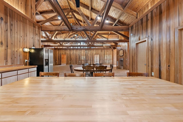 unfurnished dining area with beamed ceiling, wooden walls, and wooden ceiling