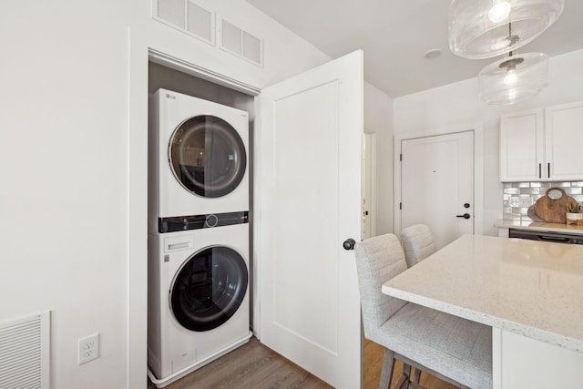 clothes washing area featuring stacked washer / dryer and dark wood-type flooring