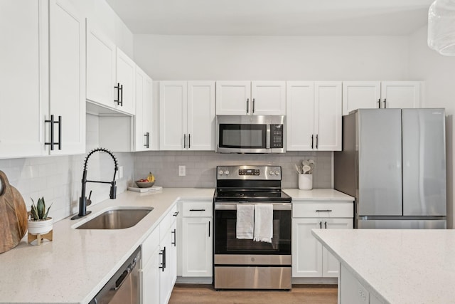 kitchen with stainless steel appliances, sink, white cabinets, and backsplash