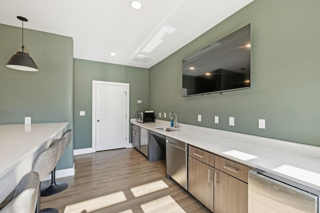 kitchen with pendant lighting, sink, light wood-type flooring, and appliances with stainless steel finishes