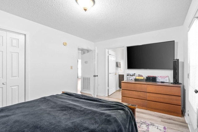 bedroom with light hardwood / wood-style floors, connected bathroom, a textured ceiling, and a closet