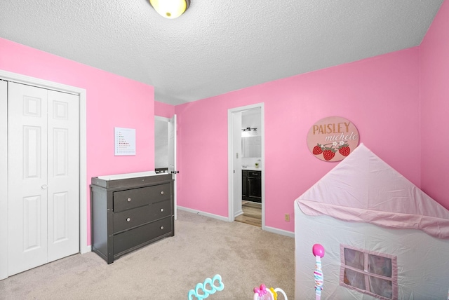 carpeted bedroom with ensuite bath, a closet, and a textured ceiling