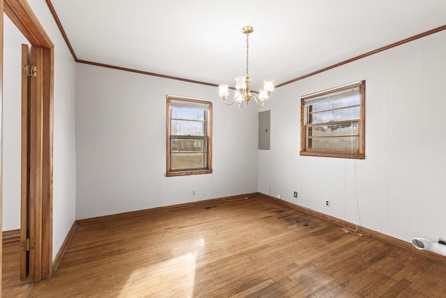 empty room featuring hardwood / wood-style flooring, crown molding, electric panel, and a chandelier