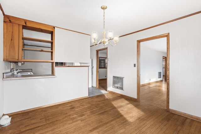 unfurnished dining area with hardwood / wood-style flooring, ornamental molding, sink, and a chandelier