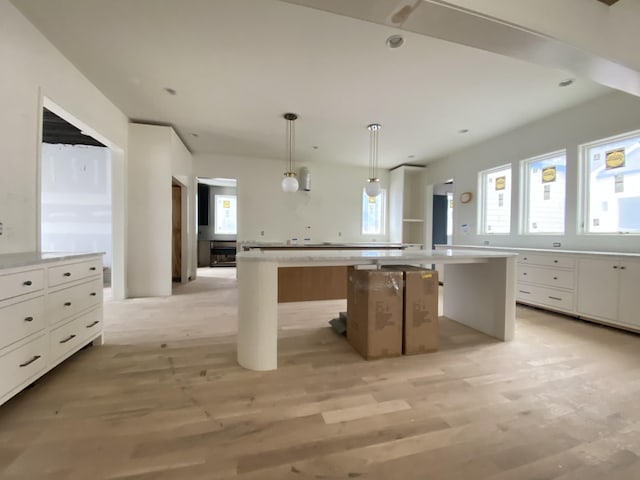 kitchen featuring pendant lighting, a kitchen breakfast bar, white cabinets, and a kitchen island