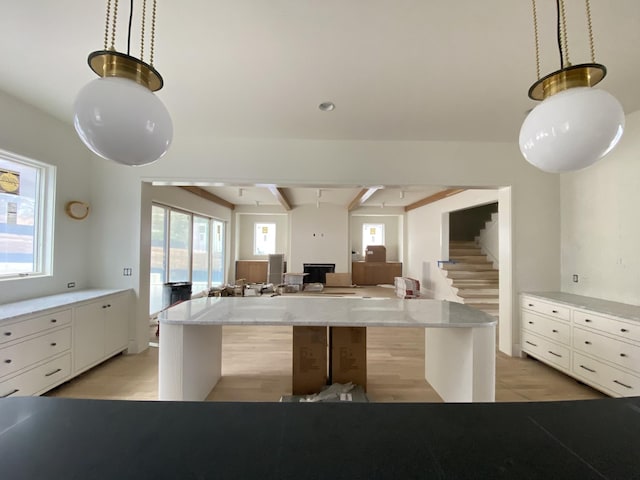 kitchen with a kitchen island, beam ceiling, hanging light fixtures, and white cabinets