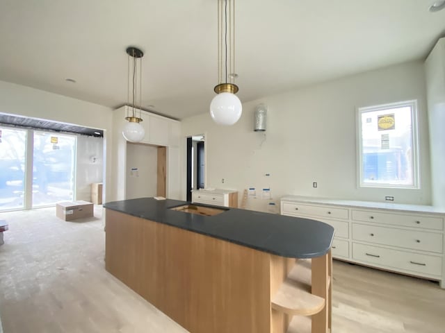 kitchen featuring hanging light fixtures, light hardwood / wood-style floors, a center island, and white cabinets