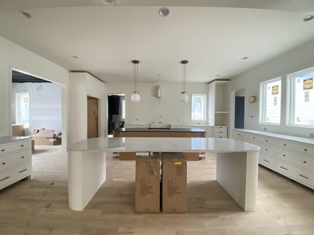 kitchen featuring white cabinetry, a kitchen island, pendant lighting, and a kitchen breakfast bar