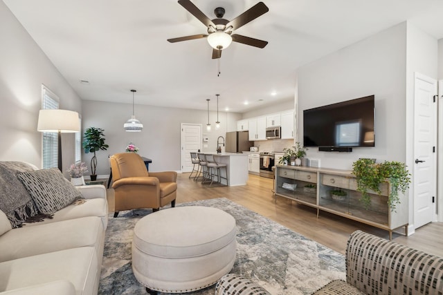 living room with ceiling fan and light hardwood / wood-style flooring