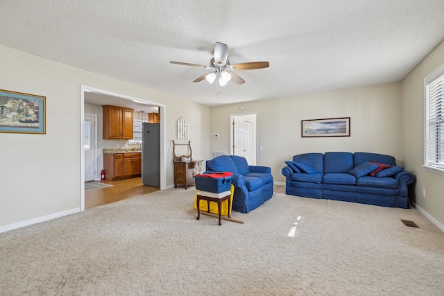 living room with ceiling fan, light colored carpet, and a textured ceiling