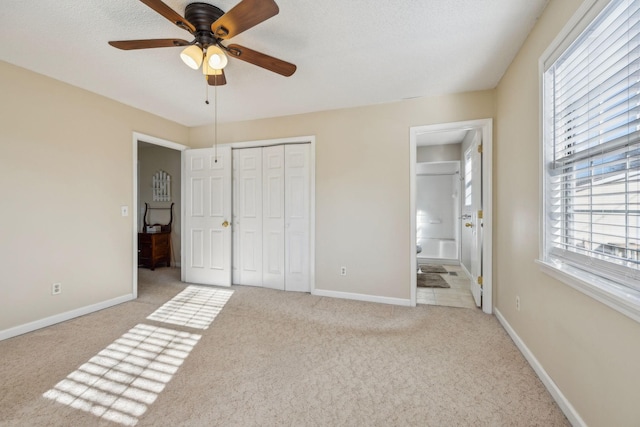 unfurnished bedroom with light carpet, connected bathroom, a closet, and ceiling fan