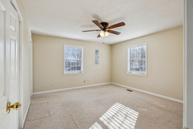 spare room featuring ceiling fan, a healthy amount of sunlight, electric panel, and light carpet