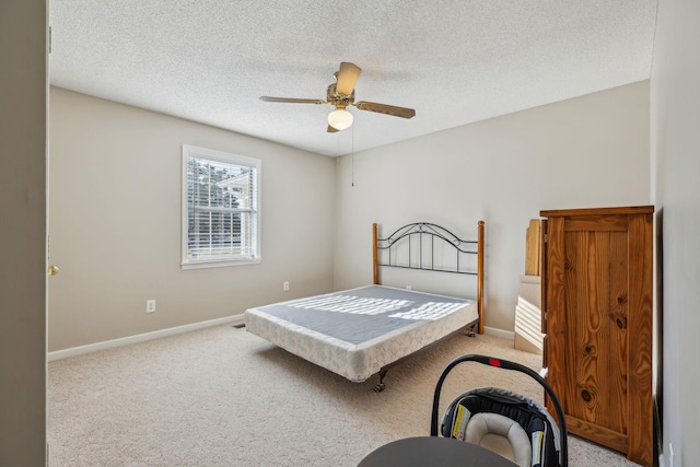 carpeted bedroom featuring ceiling fan and a textured ceiling