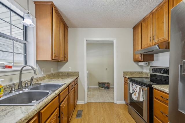 kitchen with sink, decorative light fixtures, light hardwood / wood-style flooring, a textured ceiling, and stainless steel appliances