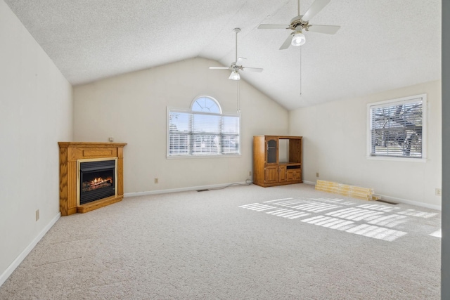 unfurnished living room with ceiling fan, light colored carpet, vaulted ceiling, and a textured ceiling