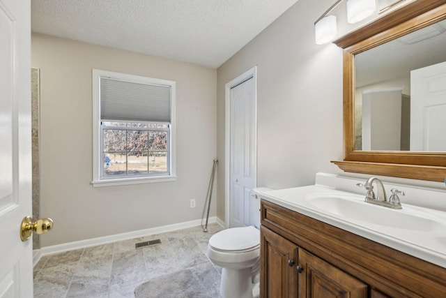 bathroom featuring vanity, a textured ceiling, and toilet