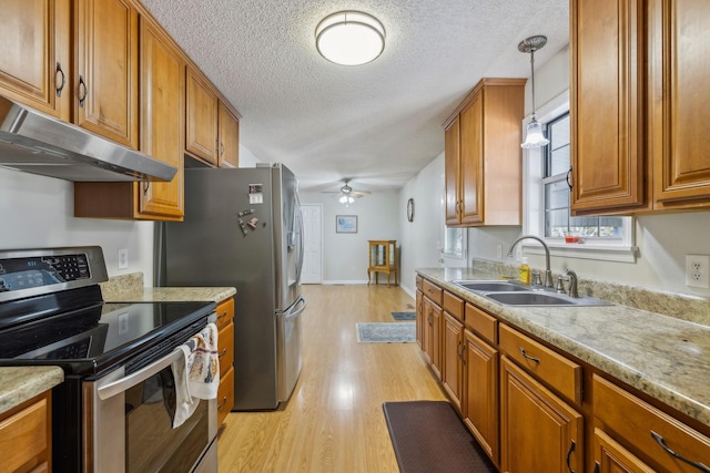 kitchen featuring appliances with stainless steel finishes, pendant lighting, sink, ceiling fan, and light hardwood / wood-style floors