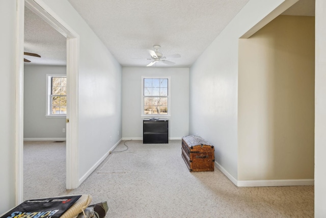 interior space featuring ceiling fan, light colored carpet, and a textured ceiling