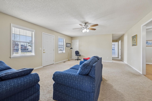 living room featuring ceiling fan, light colored carpet, and a textured ceiling