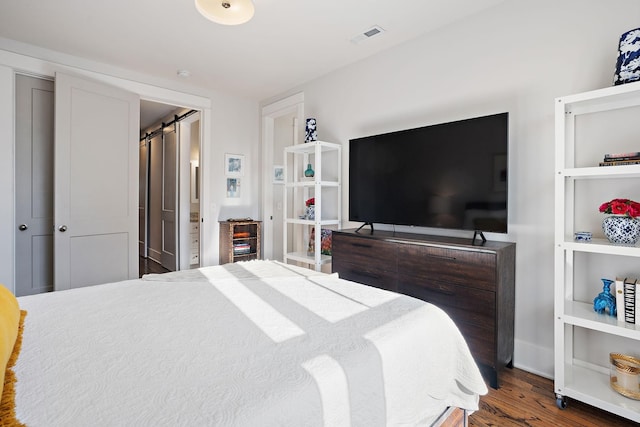 bedroom with dark hardwood / wood-style flooring and a barn door