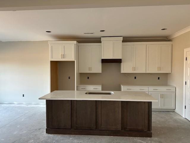 kitchen featuring white cabinetry, crown molding, and a center island with sink