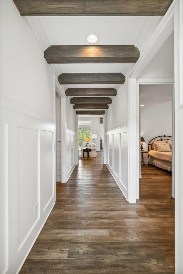 corridor with dark hardwood / wood-style floors and beam ceiling