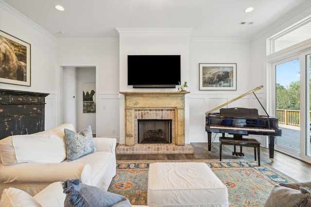 living room featuring hardwood / wood-style flooring, crown molding, and a fireplace