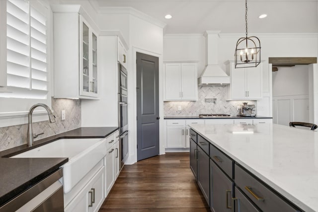 kitchen with white cabinetry, decorative light fixtures, and dark stone counters