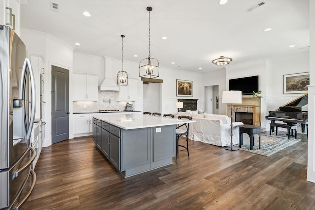 kitchen featuring stainless steel refrigerator with ice dispenser, gray cabinetry, decorative light fixtures, a center island, and white cabinets