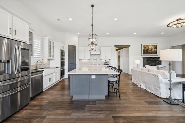 kitchen with pendant lighting, appliances with stainless steel finishes, white cabinetry, a kitchen island, and decorative backsplash