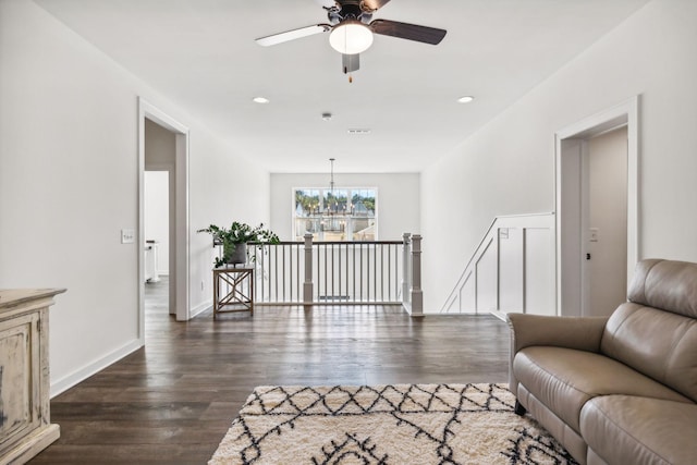 living room with dark hardwood / wood-style flooring and ceiling fan with notable chandelier