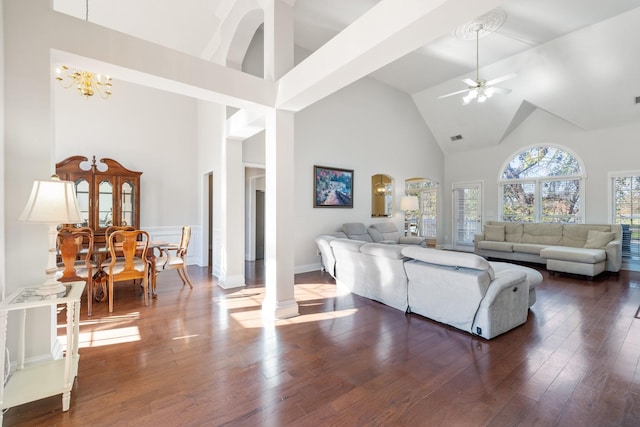 living room featuring ceiling fan with notable chandelier, dark hardwood / wood-style floors, high vaulted ceiling, and decorative columns