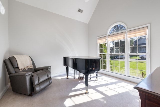 sitting room with light carpet and high vaulted ceiling