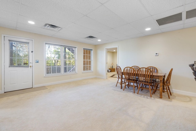 dining space featuring light carpet and a drop ceiling