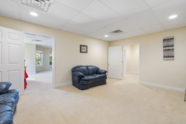 sitting room featuring light carpet and a drop ceiling