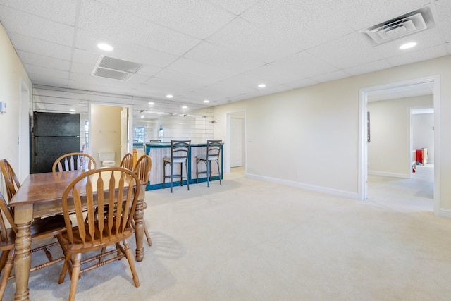 carpeted dining area featuring a drop ceiling